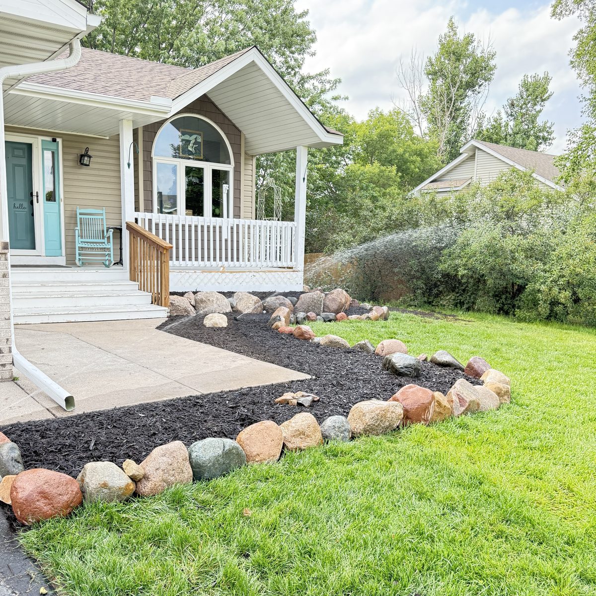 After: clean boulder edging and fresh black mulch bed by Viridizs — Elk River, MN